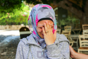 This refugees is crying as she remembers the events that occurred as she moved to Greece including the death of her husband.