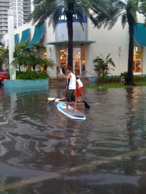 Locals take advantage of the flooded streets to paddle board.