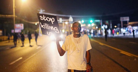 Protester holding up a sign that says "Stop killing us."