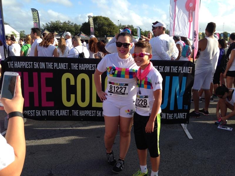 Two participants pose in front of the Color Run sign before the race.