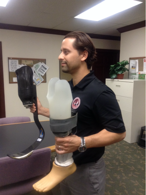 Gaunaurd holding two different models of prosthetic limbs.