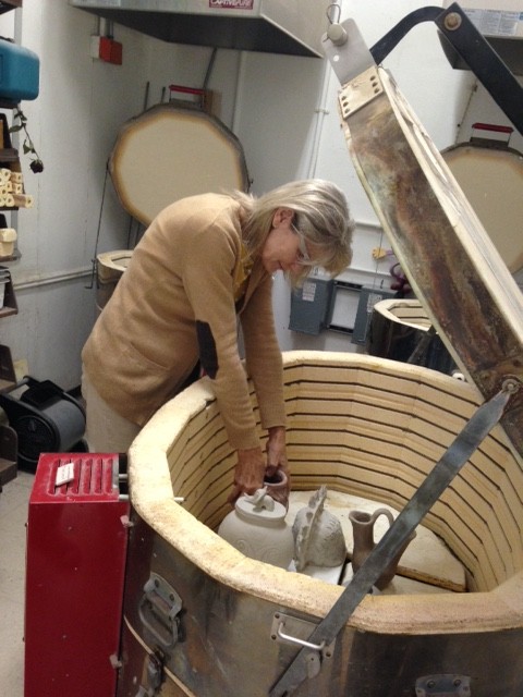 Ms. Stapleton placing students clay pieces in the kiln.