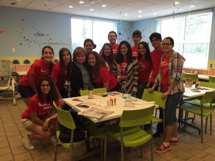 Members huddle around their sponsor, Ms. Verazain, before arts and crafts with the children.