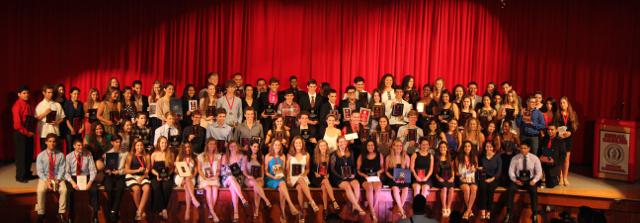 Award recipients gather on stage to showcase their awards.