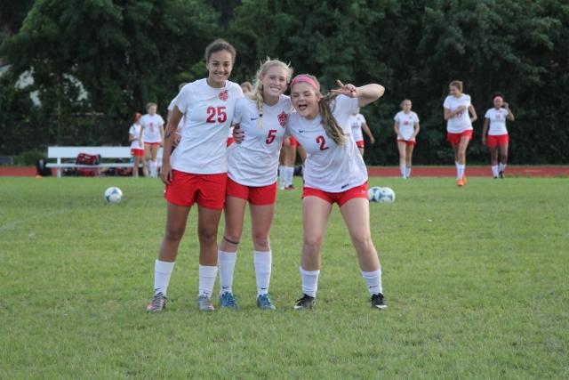 Three of the girls soccer team very satisfied with themselves after their victory