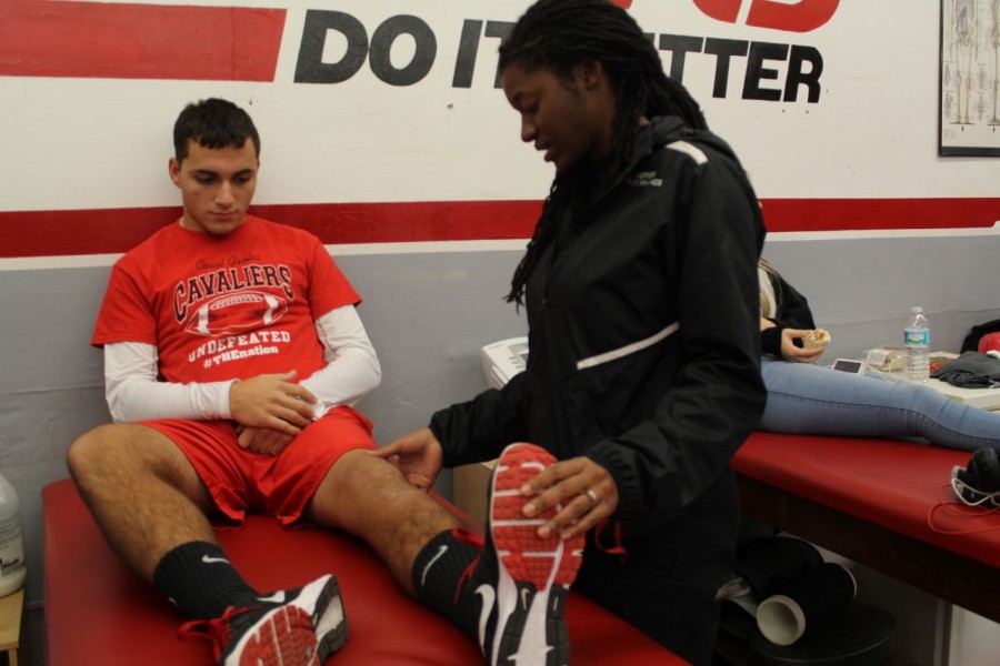 Sophomore Sebastian Riella measures his progress with the help of Athletic Trainer, Shannon Singleton during lunch treatments.