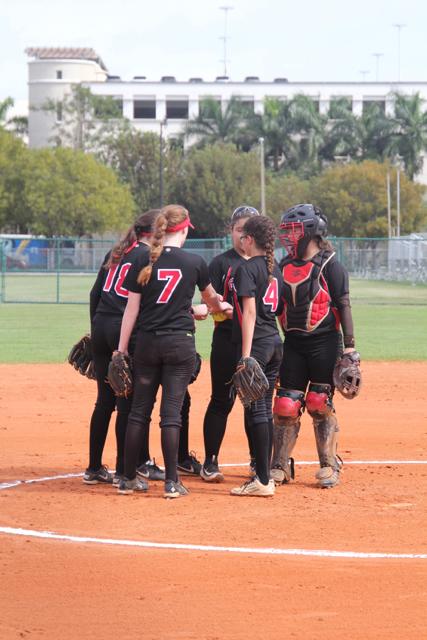 The softball team huddles up as they begin their inning 