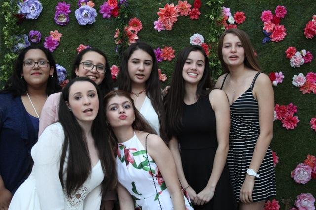 Students pose together in front of a flowery back drop.