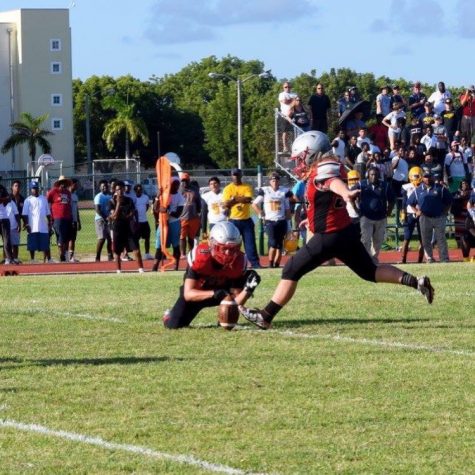 Senior Daniel Enriquez holds ball as freshman Matthew Enriquez kicks.