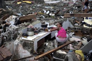 Woman in Baracoa, Cuba rummaging through the remains of her home.