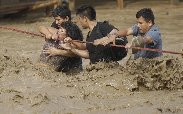 A group of people stranded in a mudslide hold on to a rope as they make their way to safety.