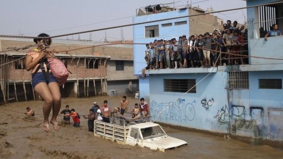 Hundreds of boys gather on the roof of a building to avoid the dangerous flood waters below.