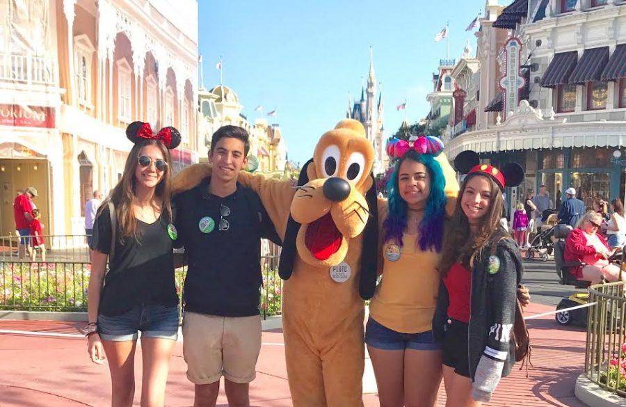 Seniors take a photo with Disney character, Pluto, in Disney's Magic Kingdom park.