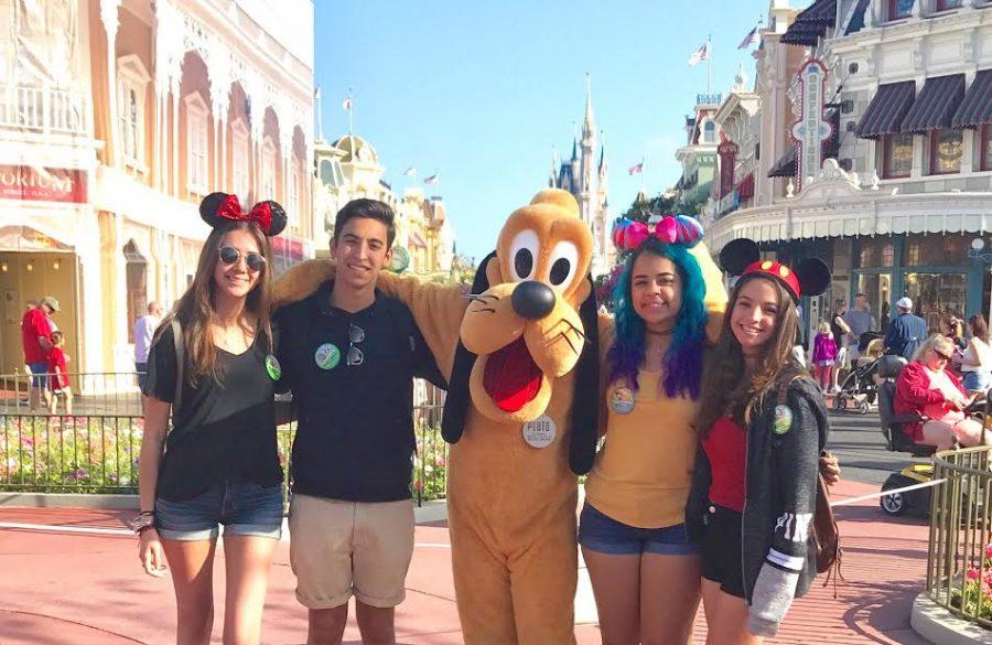 Seniors take a photo with Disney character, Pluto, in Disneys Magic Kingdom park.