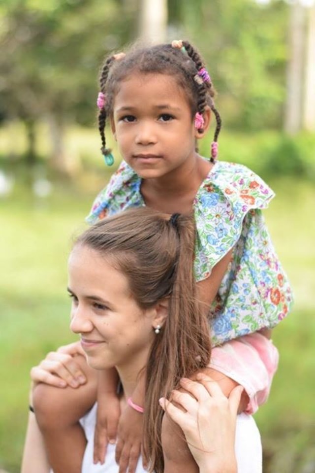 Marina Torras stands with a child from the village.