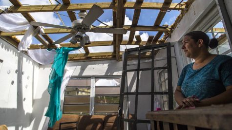 A woman stands, in what used to be her home, after Hurricane Maria has passed. 