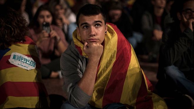 Un joven escucha la comparecencia de Mariano Rajoy en una pantalla de televisión de Barcelona el día del intento de referéndum en Cataluña.