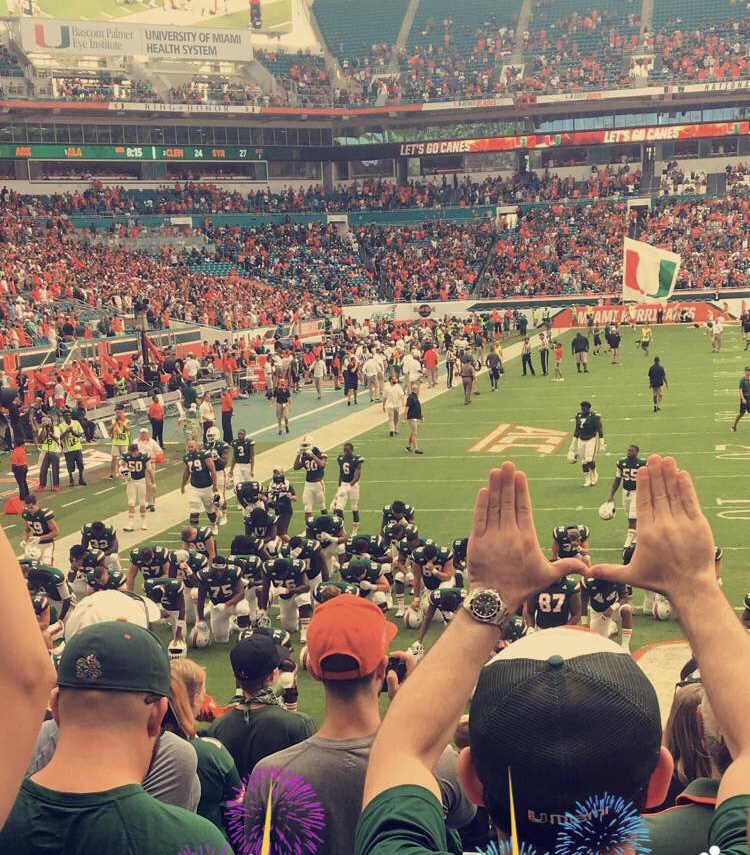 University of Miami fans raise tehir hands in celebration the team's win. 