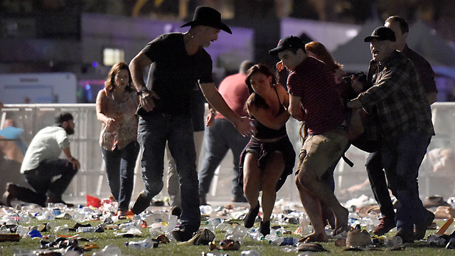 LAS VEGAS, NV - OCTOBER 01: (EDITORS NOTE: Image contains graphic content.) People carry a peson at the Route 91 Harvest country music festival after apparent gun fire was heard on October 1, 2017 in Las Vegas, Nevada. There are reports of an active shooter around the Mandalay Bay Resort and Casino.  (Photo by David Becker/Getty Images)