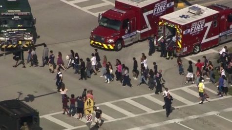 Students at high school being led outside the school onto the street near firetrucks.