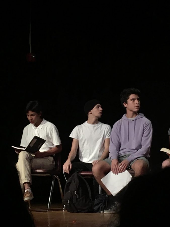 Emilio Gutierrez, Tristan Breaux, and Dan Leiferman sit on stage during one of the shorts written by troupe.