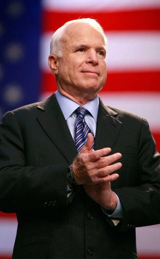 Senator John McCain stands in applause at a political event.  