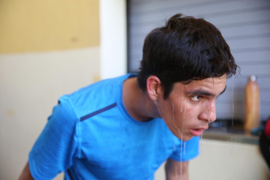 Junior Braulio Gonzales captured as he poured water on his head after cross country practice at the front of the new building.