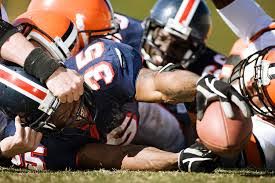 Football players from opposing teams pile on top of each other in an attempt to get the ball but sustain severe brain damage in the process. 