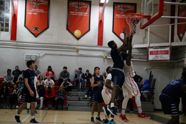 A Cavalier Basketball player makes his way up to the rim and scores a field goal.