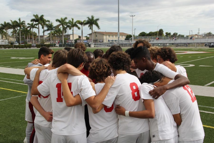 The Cavalier soccer team huddling in unison to kick-start a game