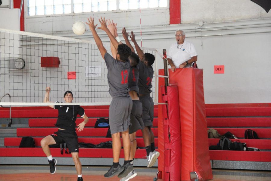Three Cavaliers leap in the air to defend a volley, aiming to tally a point for their team.