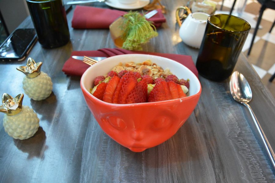 La Muses acai bowl is plated in a vibrant bowl that matches the artistic atmosphere and is filled with fruits and nuts.