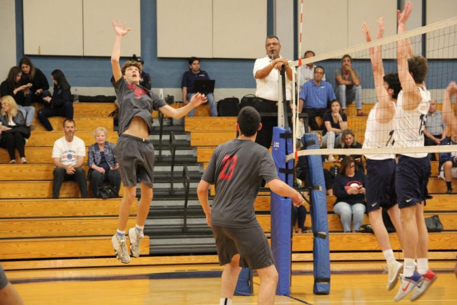 Senior Matthew Wagner leaps in the air, preparing to strike the ball, as two Explorers aim to defend his hit.
