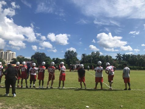 The varsity football team line up on the field, working hard and running their plays during practice.