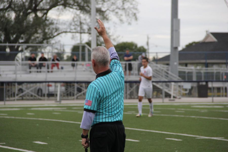 The referee at a Cavalier Soccer game blows his whistle, announcing halftime.