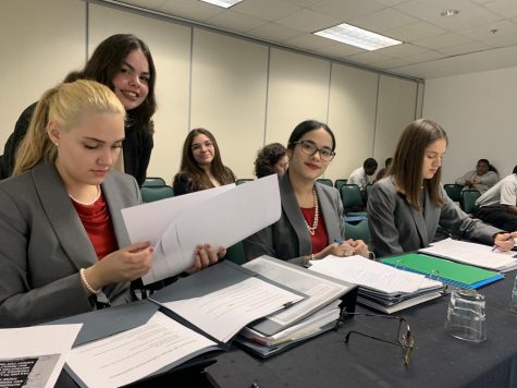 Gables' mock trial team prepares its case files and evidence for their presentations as they wait for the trial to start.