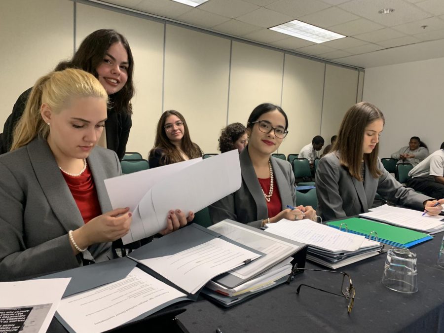 Gables mock trial team prepares its case files and evidence for their presentations as they wait for the trial to start.