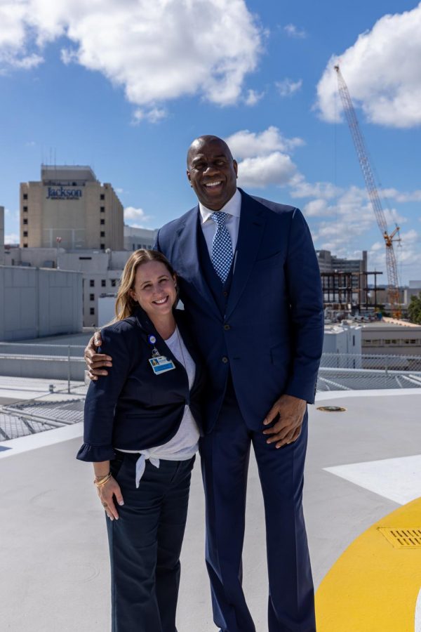 Jennifer Mooney Piedra standing next to Magic Johnson. Piedra is an alumna of Coral Gables Senior High School, and is now at Jackson Hospital working to fight COVID-19.