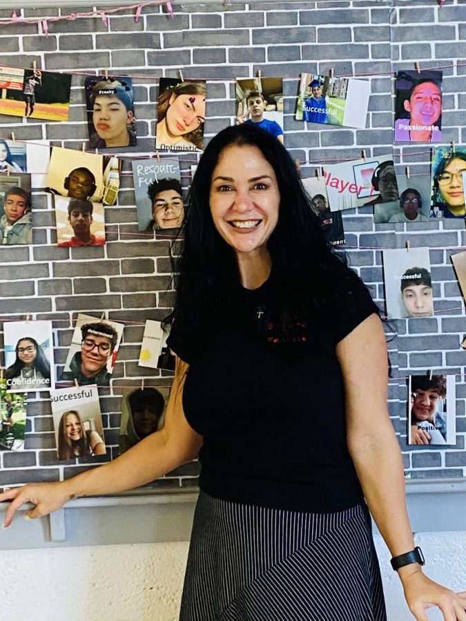 Dr. Barrocas standing in front of "The Wall of Fame" as she calls it, with pictures of all her students.