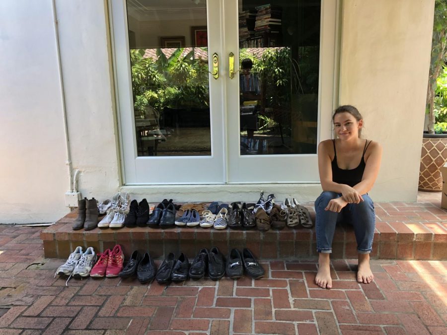 Senior Mccall Horton sitting with some of the shoes she has collected for her shoe drive Shoes for the Unshoed.