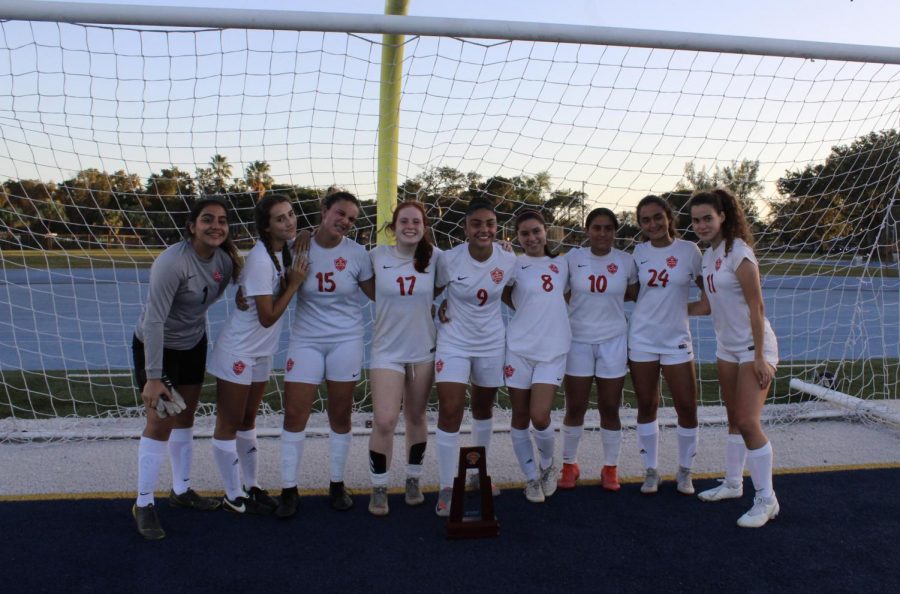 The Lady Cavaliers soccer team celebrates their 4-0 victory over Miami High with their district championship trophy