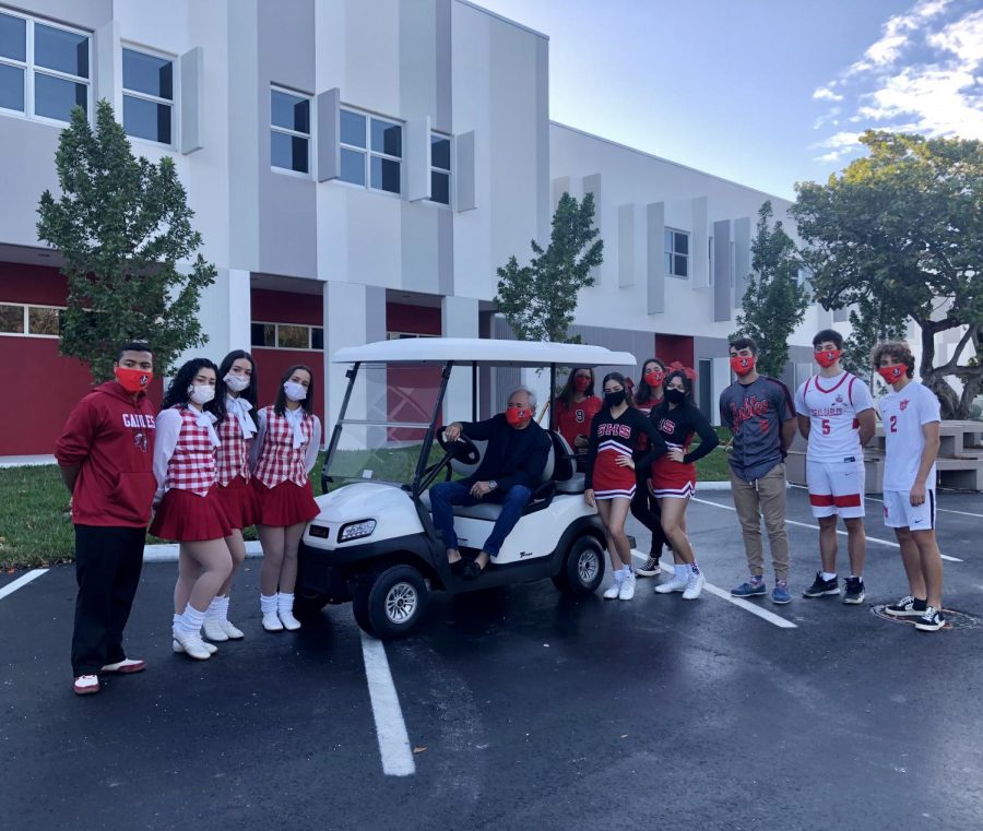 Mr.Grossman+sits+smiling+in+the+brand-new+vehicle+as+proud+Cavaliers+surround+him+and+show+off+their+school+spirit.