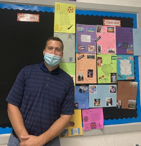 Mr. Ball-llovera stands in front of a bulletin board he decorated with projects he made his students complete about their background in hopes of getting to know the AOF students more personally.