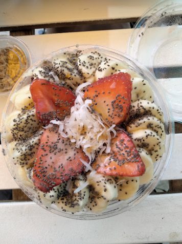 The açaí or pitaya bowl is topped with strawberries, bananas, honey, chia seeds and shredded coconut to top it off with granola on the side.