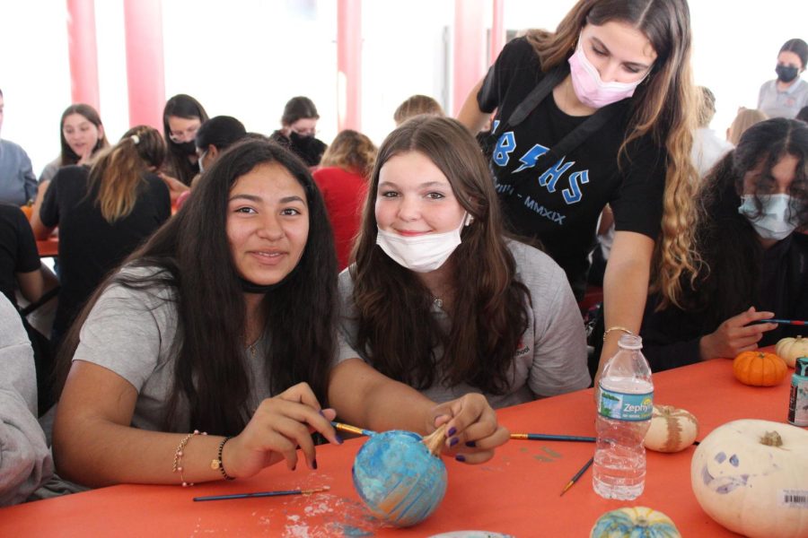 A duo of IB students de-stresses by painting a pumpkin for their favorite teacher.