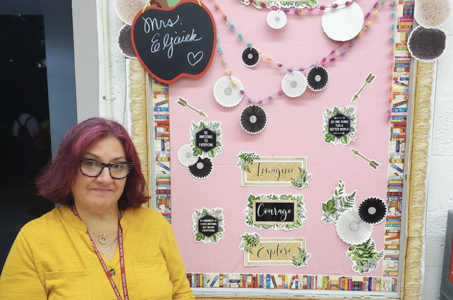 Ms. Eljaiek stands in front of her bulletin board of motivational messages that she decorated to encourage her students to work hard in and out of the classroom.