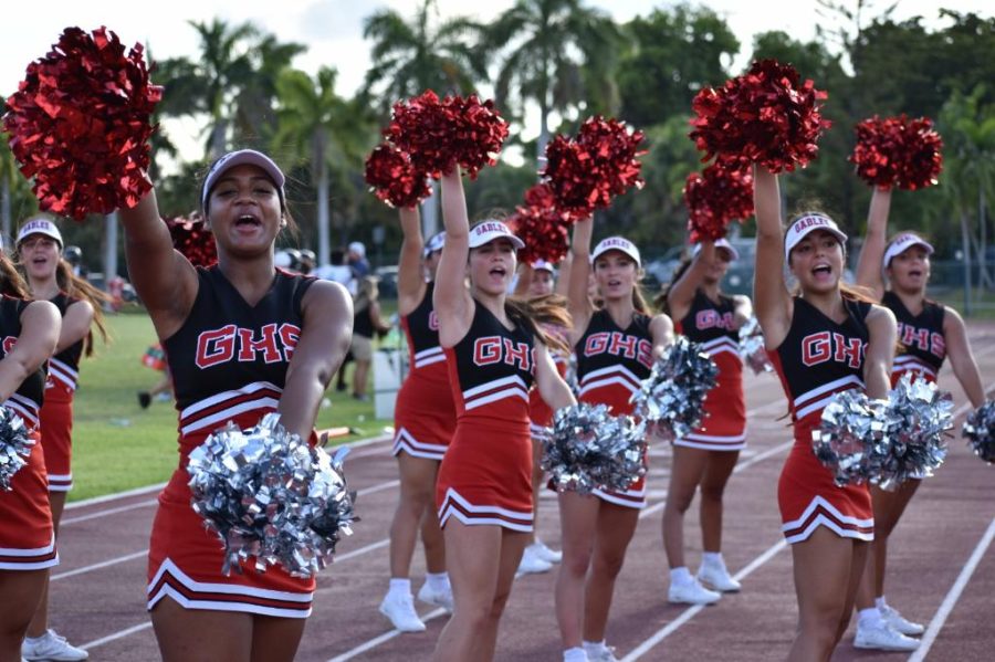 Led by Ms. Noval, cheerleaders wave their crimson and grey pom poms to demonstrate school pride.