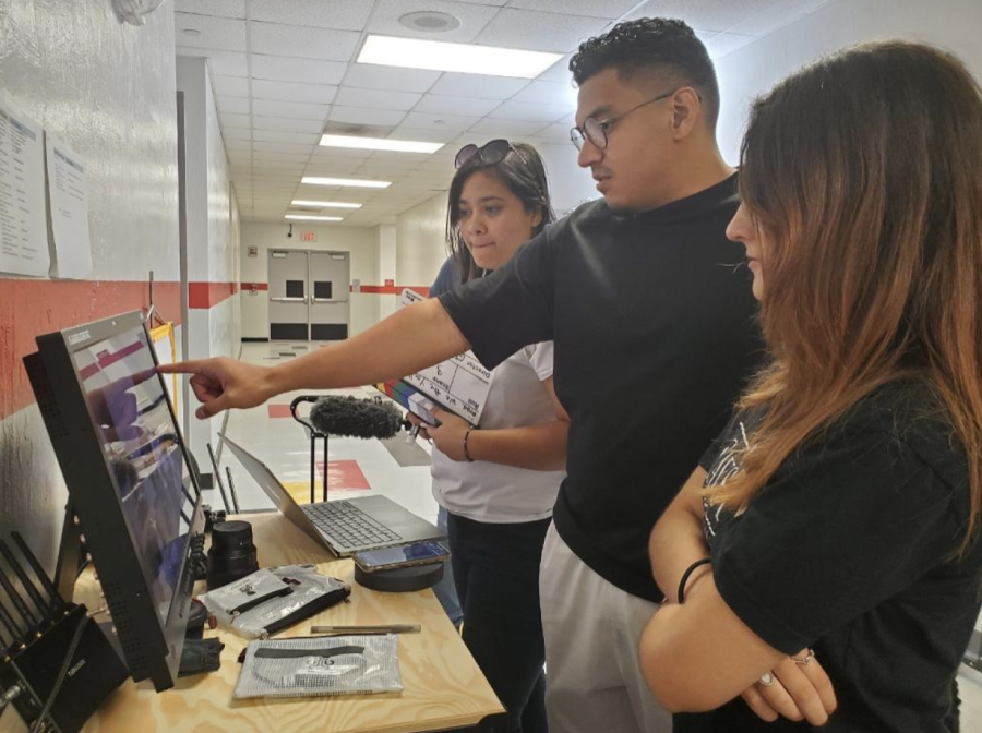 Raul Flores (middle) and CavsTV staff member Noa Belehssen (right) going over the recorded footage, along with another Gables Alumni.