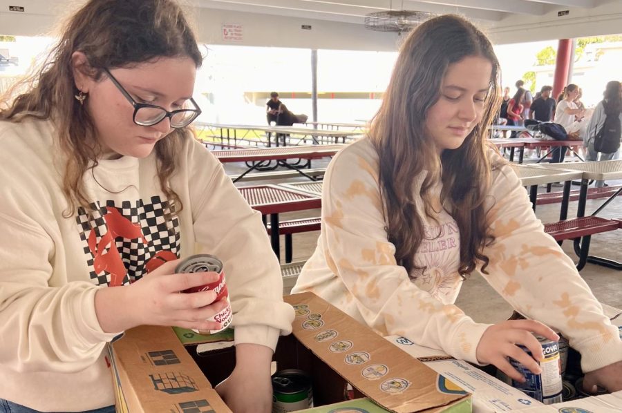 Michelle Hernandez (left) works together with Julia Pretell (right) to fill in boxes with cans during one of the food drive events. 