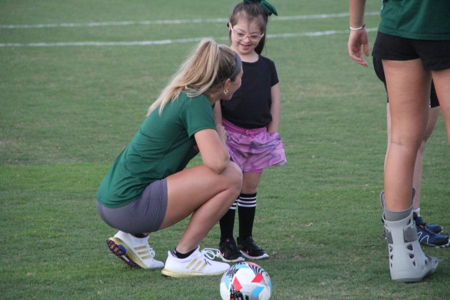 UM student Skylah Klein helped a young child with Down syndrome to play soccer.